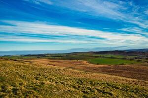 Rolling hills with lush greenery under a clear blue sky, showcasing the beauty of rural landscapes at Sycamore Gap, Northumberland, UK. photo