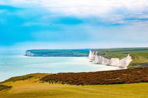 Breathtaking view of white chalk cliffs and blue sea under a clear sky at Seven Sisters, England. photo