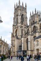 Gothic cathedral facade with pedestrians walking by on a cloudy day in York, North Yorkshire photo