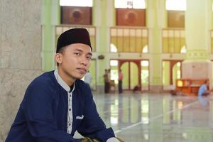 retrato de religioso asiático hombre en musulmán camisa sentado en mezquita foto
