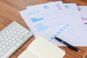 Close up of male freelance worker hand working on laptop and pointing with finger on analysis data with business graph and chart of information diagram on office desk in the morning photo