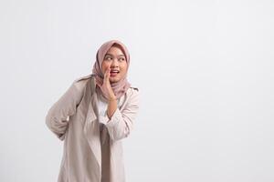 Portrait of excited Asian hijab woman in casual suit screaming announcement and whispering gossip. Businesswoman concept. Isolated image on white background photo