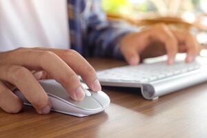 Close up of male hand using wireless keyboard and mouse in office desk. Casual working concept photo