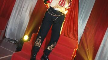 Performer in a costume on stage with red curtains and spotlight, concept of theater arts and entertainment. video