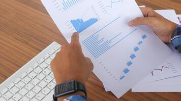 Close up of male freelance worker hand working on laptop and pointing with finger on analysis data with business graph and chart of information diagram on office desk in the morning photo