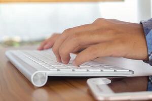 Close up of male hand using wireless keyboard and mouse in office desk. Casual working concept photo