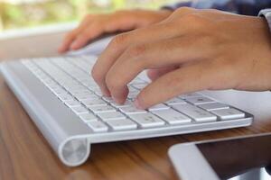 Close up of male hand using wireless keyboard and mouse in office desk. Casual working concept photo