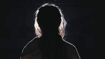 Silhouette of a woman with rim light, against a dark background. video