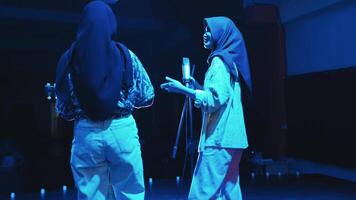 dos personas en escenario, uno participación un micrófono y el otro un guitarra, con un atención en cultural diversidad. video