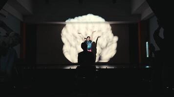 silueta de un persona con elevado brazos a un concierto con etapa luces y entusiasta multitud en el antecedentes. video