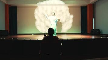 Silhouette of a person sitting in a dark room watching a brain projection on a screen. video