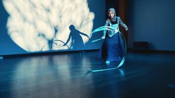 Silhouette of a child playing with a hoop in a dimly lit room, casting a shadow on the wall. video