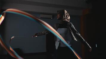 Silhouette of a person practicing archery in a dark indoor setting, focusing on the bow and arrow at full draw. video