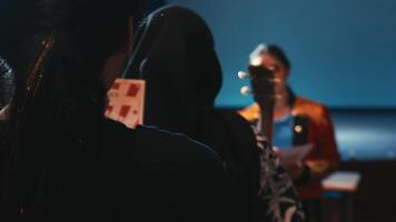 Silhouetted audience member holding cards with a blurred speaker in the background. video