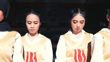 Group of young women in uniform with serious expressions, possibly a dance or performance group. video