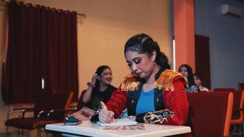 Focused woman writing notes with audience in background at a seminar or conference setting. video