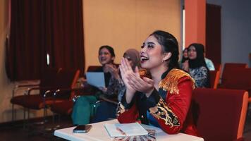 Enthusiastic woman clapping at an event with audience in background video