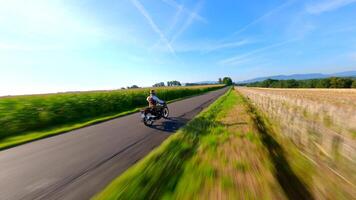 fpv av årgång motorcykel ridning en Land väg genomgång fält i sommar video