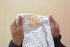 men holding white dirty bed cover, showing making stain photo