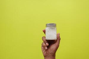 top view of holding a salt container on yellow background photo