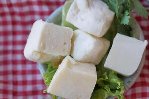 Food plate of cheese cubes and lettuce on checkered tablecloth photo