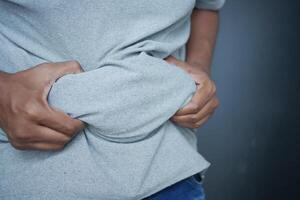 man's hand holding excessive belly fat, overweight concept photo