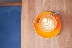 top view of orange color coffee cup on wooden plate. photo