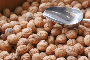 A scoop of walnuts, a superfood, rests on a stack of nuts seeds photo