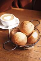 Three bread rolls rest in a black bowl on the table photo