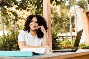 Happy student smiling posing sitting on a chair in a desk in a campus. photo