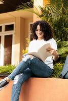 Young student with curly hair making notes in a book, Latin American female student doing homework. photo