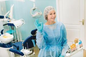 the dentist stands in his office and shows the OK sign photo