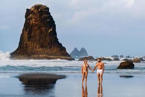 A couple in love walks along Benijo Beach, Tenerife, Spain . A popular place among locals and tourists photo