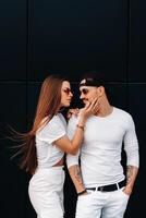 A beautiful couple in love in white stylish clothes are walking in the city photo