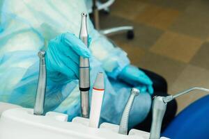 a dentist wearing gloves in the dental office holds a tool before working photo