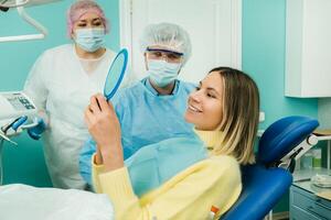 el dentista muestra el cliente el resultados de su trabajo en el espejo foto