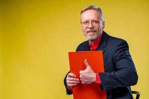 Middle aged businessman standing and holding file folder. Horizontal format isolated on yellow background. photo