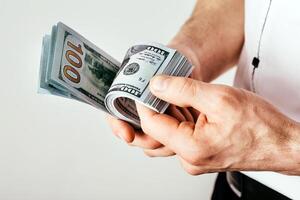 A businessman holds money in his hands and counts his income. Money is stacked in dollar bills photo