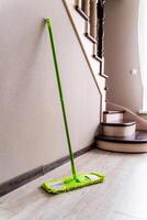 Green mop on a wall and stairs background. Cleaning living room. photo