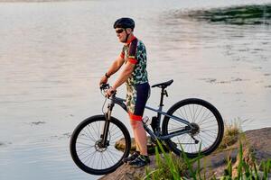 Mountain biker looking at view and traveling on bike. Lake landscape. photo