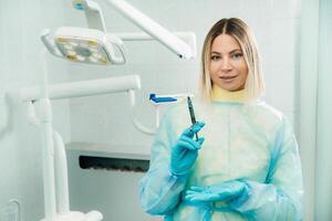 The dentist holds an injection syringe for the patient in the office photo