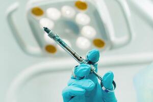 close-up of a dentist's hand holding an injection syringe for a patient in the office photo