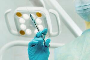 close-up of a dentist's hand holding an injection syringe for a patient in the office photo