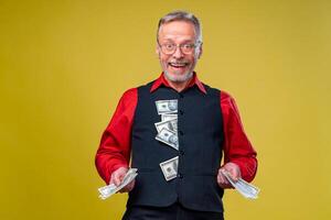 retrato de contento y blanco dientes sonrisa mayor antiguo negocio hombre participación dinero en manos, vestido en rojo camisa, aislado en amarillo antecedentes. humano emociones y facial expresiones foto