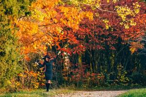 Beautiful woman in a dark dress stands in a park on the background of yellowed trees. Autumn background. photo