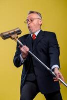 Adult man singing in mop. Holding broom like microphone. Man in suit. photo