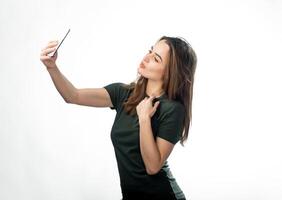 Young woman makes a selfie in a studio. Closeup. Isolated background. Beautiful brunette. Hand on neck. photo