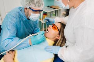 un masculino dentista con dental herramientas simulacros el dientes de un paciente con un asistente. el concepto de medicamento, odontología y cuidado de la salud foto