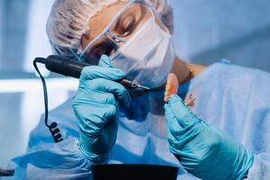 un dental técnico en protector ropa es trabajando en un protésico diente en su laboratorio foto