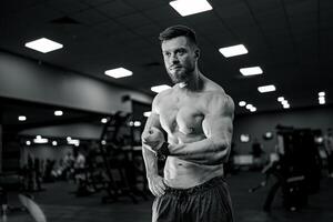 Strong bodybuilder doing exercise in gym. Young topless muscular man working out. photo